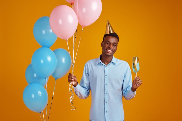 funny man cap holding glass beverage yellow background smiling male person got surprise event birthday celebration balloons decoration 266732 27736